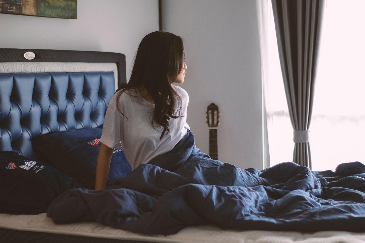 Người phụ nữ ngồi một mình trong quán cà phê đông người, tay cầm điện thoại, ánh mắt xa xăm, thể hiện sự cô đơn giữa đám đông ảo.
