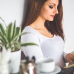 Minh Khuê đang ngồi thư giãn với sở thích không cần giỏi của mình, một cuốn sách và ly trà trên bàn